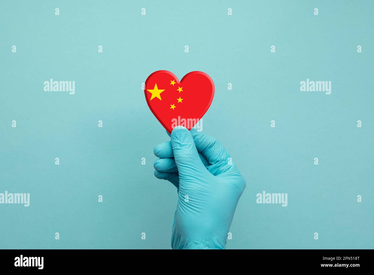 Mani che indossano guanti chirurgici protettivi che tengono il cuore della bandiera cinese Foto Stock