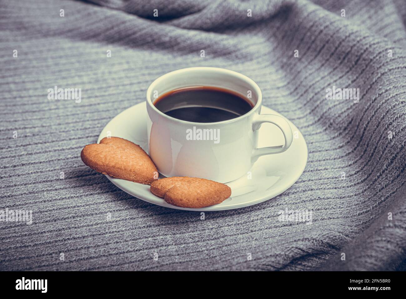 Una tazza di caffè su un tavolo coperto da una coperta. Foto Stock