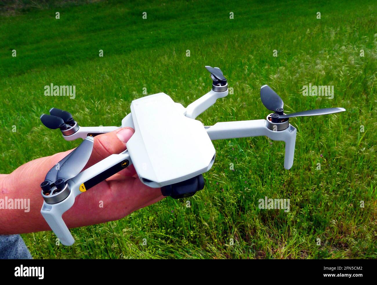 Piccolo drone bianco da fotocamera tenuto in mano maschile. Eliche nere. Vista closeup. Eliche fisse. Tecnologia e fotografia aerea Foto Stock