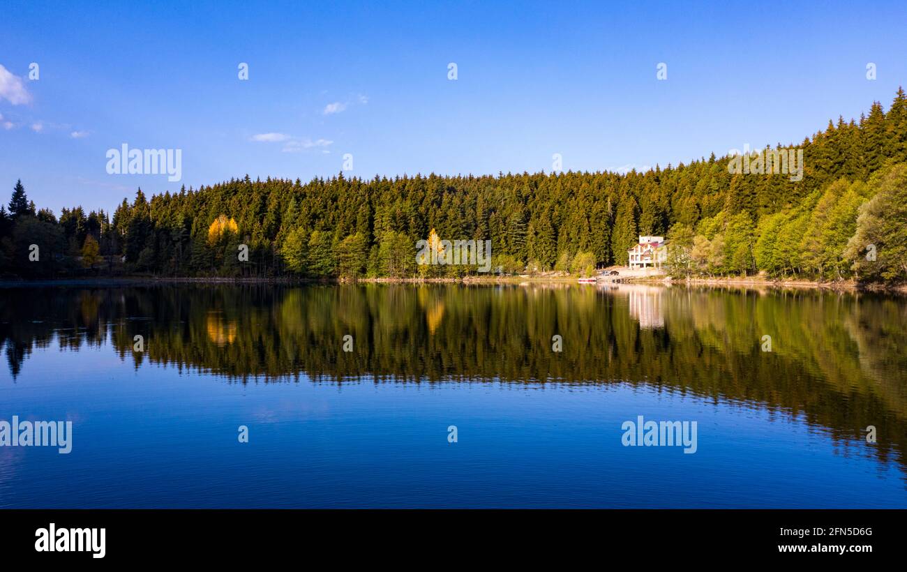 Un'affascinante foto panoramica di un paesaggio che cattura Artvin Savsat in Turchia. Il lago limpido vicino ad un sentiero che ha un edificio bianco di fronte ad un Foto Stock