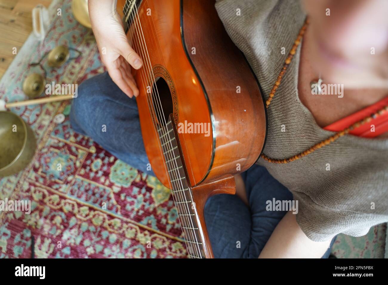 Ragazza con chitarra seduta sul pavimento in posa Yogi. Foto Stock