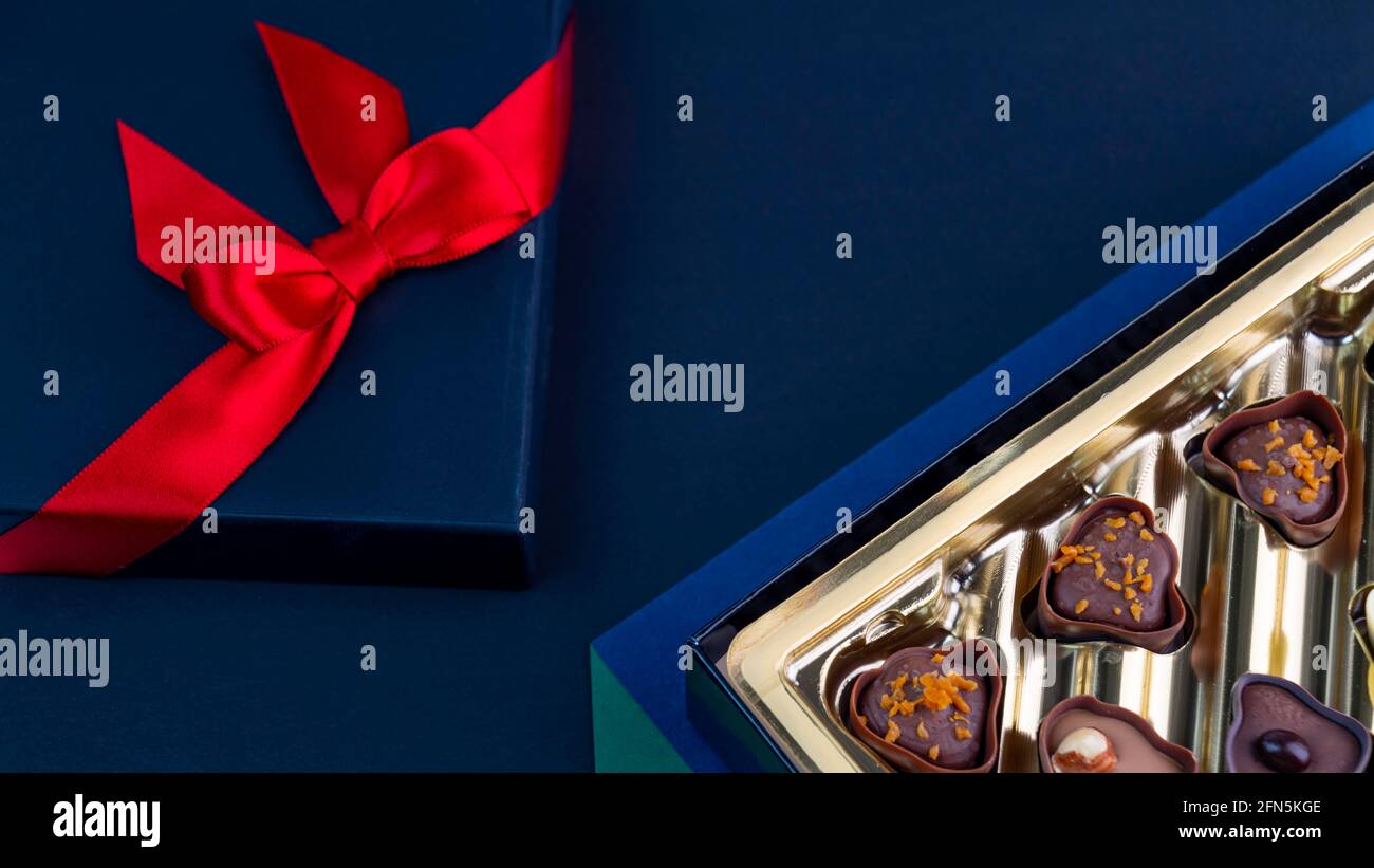 Cioccolatini in scatola d'oro con un arco rosso Foto Stock