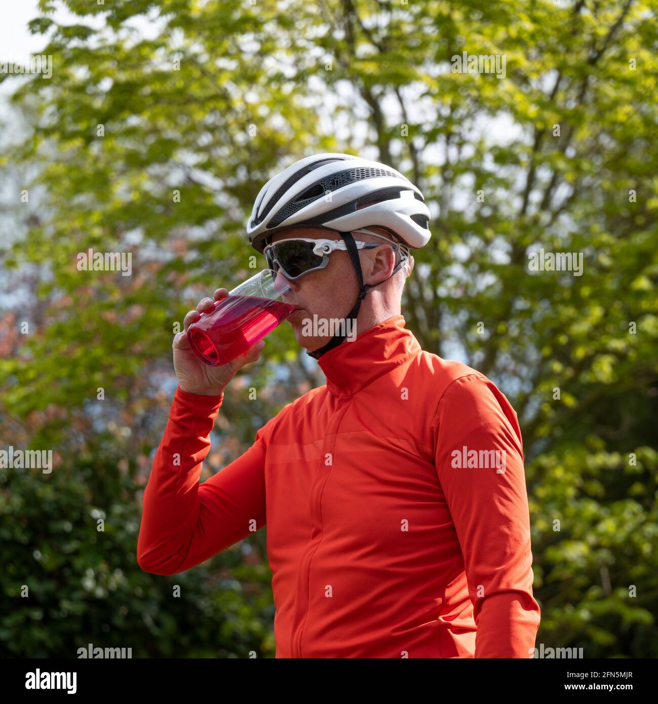 Ciclista maschile che ha una bevanda rinfrescante a una fermata di riposo. Foto Stock