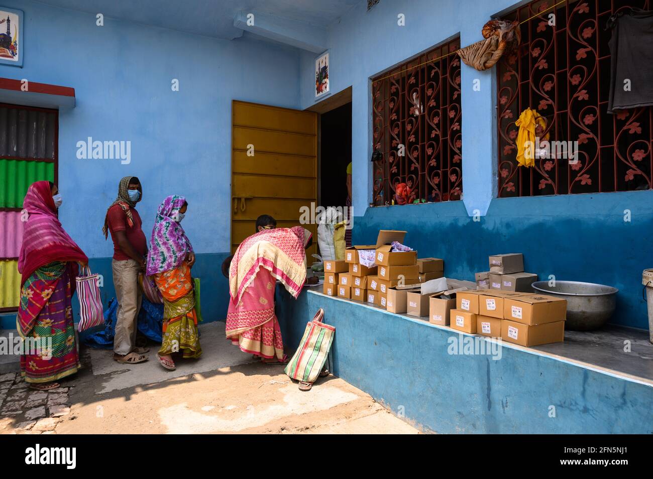 Il coronavirus è entrato nelle zone rurali dell'India. Essendo un centro di quarantena in una scuola primaria di villaggio, gli studenti stanno avendo scarpe in distribuzione annuale da parte del governo del Bengala Occidentale in una casa vicina dalla scuola al villaggio di Nabin Nagar, Tehatta, Bengala Occidentale; India il 12/05/2021. Le scarpe degli studenti sono state date ai loro genitori a causa della minaccia del coronavirus in India. La maggior parte di loro sono guardiani analfabeti e al di sotto della soglia di povertà. Il programma è fatto con la sicurezza di precauzione maggiore dal virus, come la distanza sociale con l'uso di disinfettante per le mani. (Foto di Soumyabra Foto Stock