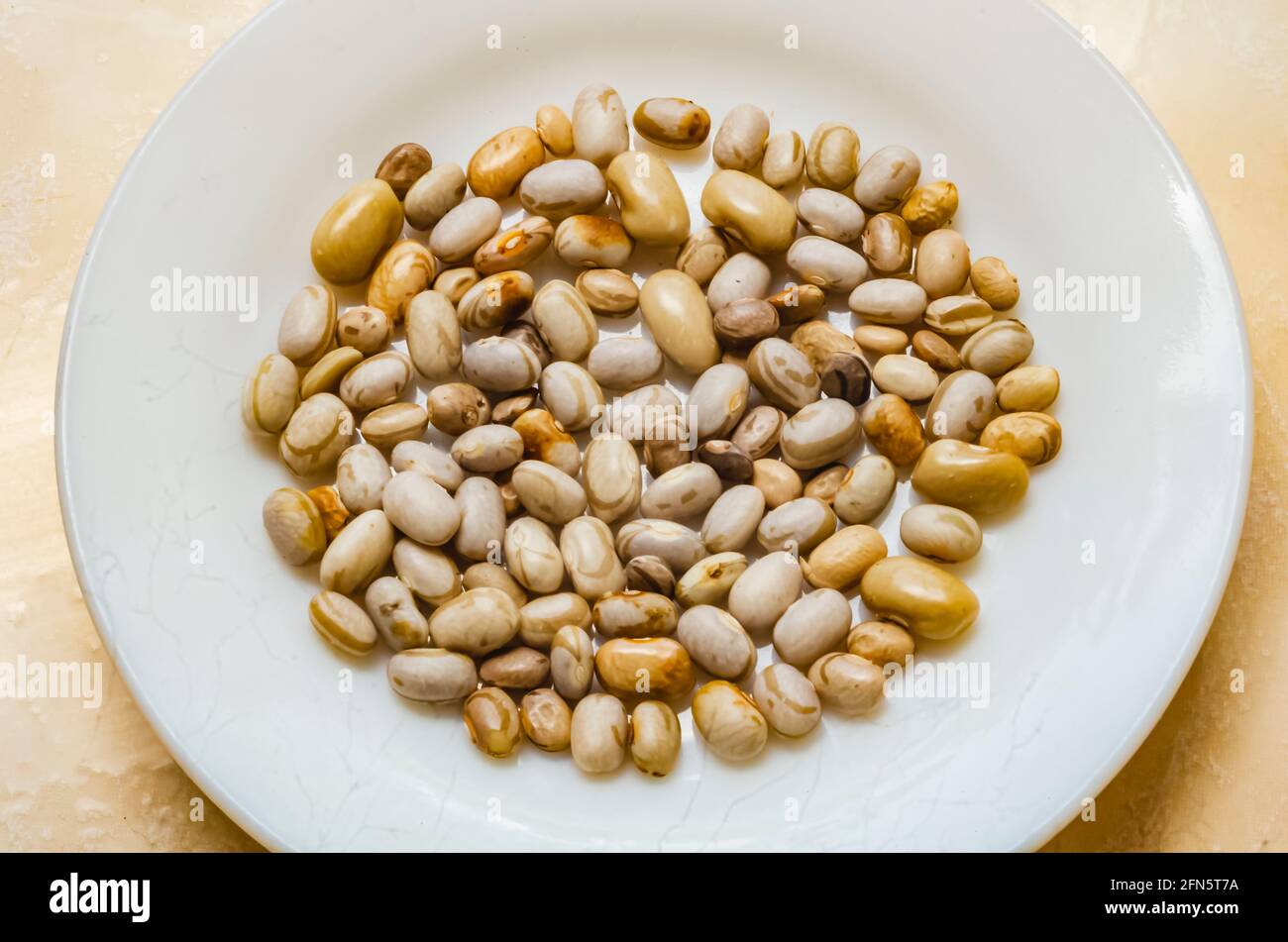 Piselli Pisum sativum (piselli divisi) in piastra bianca piccola. Foto Stock