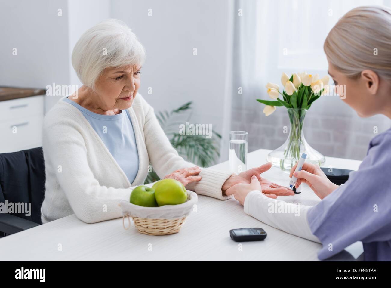 giovane infermiera che fa l'iniezione di insulina alla donna diabetica anziana a. casa Foto Stock