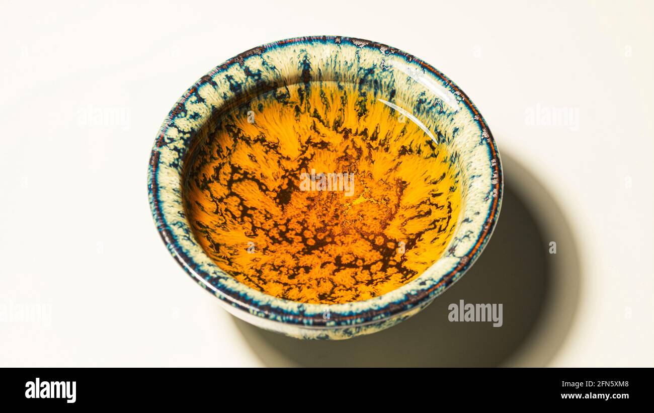 Tè in una ciotola di ceramica versata, primo piano Foto Stock