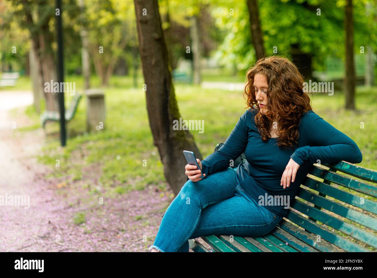 Ritratto di affascinante giovane donna rossa con smartphone in un parcheggio Foto Stock
