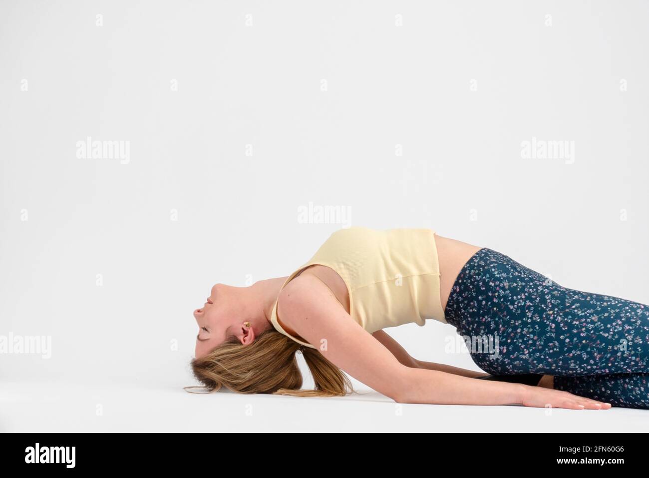 ragazza bionda che fa la postura o supta di yoga dell'eroe reclinato virasana Foto Stock