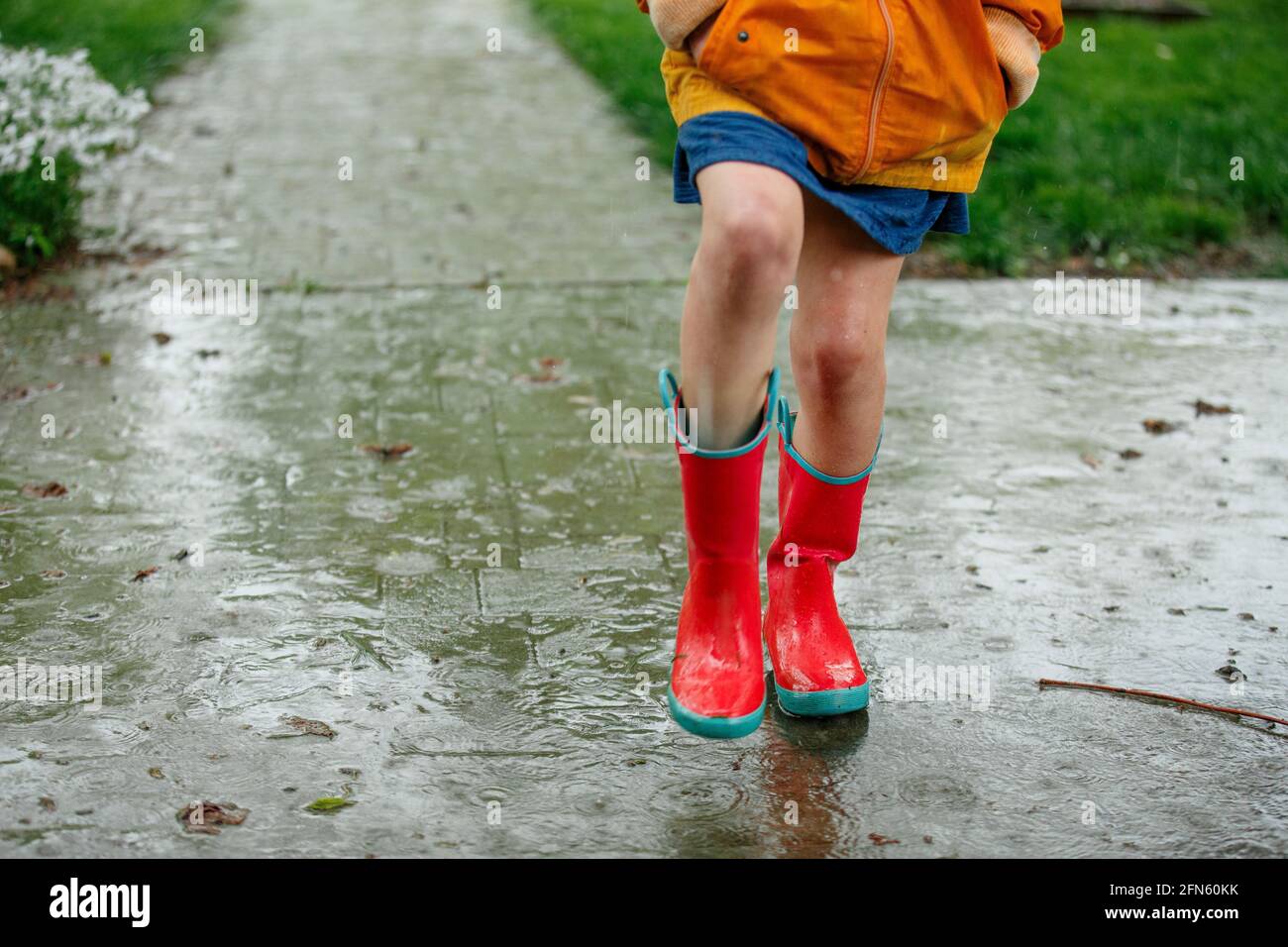 primo piano di un bambino in colorati stivali da pioggia che spruzzano la  pioggia Foto stock - Alamy