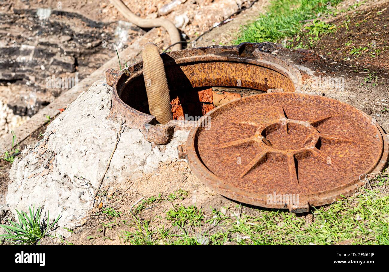 Il tubo flessibile sta pompando acqua dal pozzo di fognatura. Lavori di riparazione sulle comunicazioni delle utenze idriche urbane Foto Stock