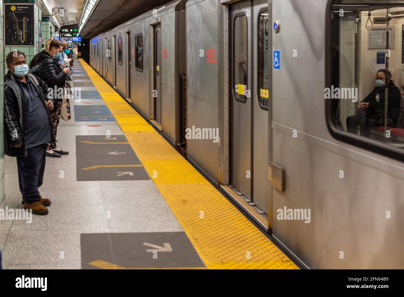 Persone reali in attesa di un treno della metropolitana TTC in una stazione durante il tempo di Coronavirus o Covid-19. TTC è l'acronimo di Toronto Transit Commission in Canada Foto Stock