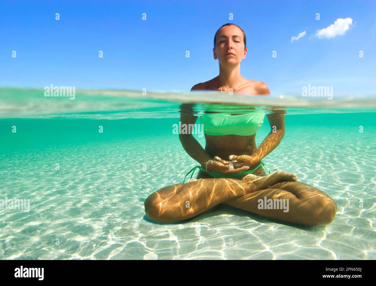 Mezza sopra e metà sotto la foto d'acqua di una Donna Fare yoga nel mare turchese della Sardegna Foto Stock