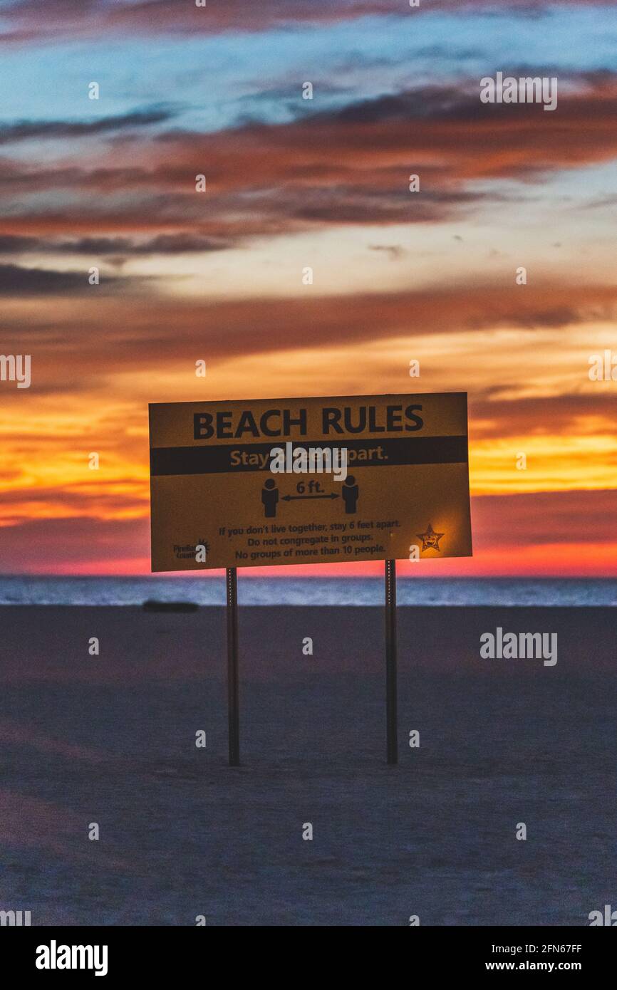 Regole della spiaggia soggiorno 6 piedi di distanza cartello di avvertimento spiaggia contro cielo vibrante al tramonto Foto Stock