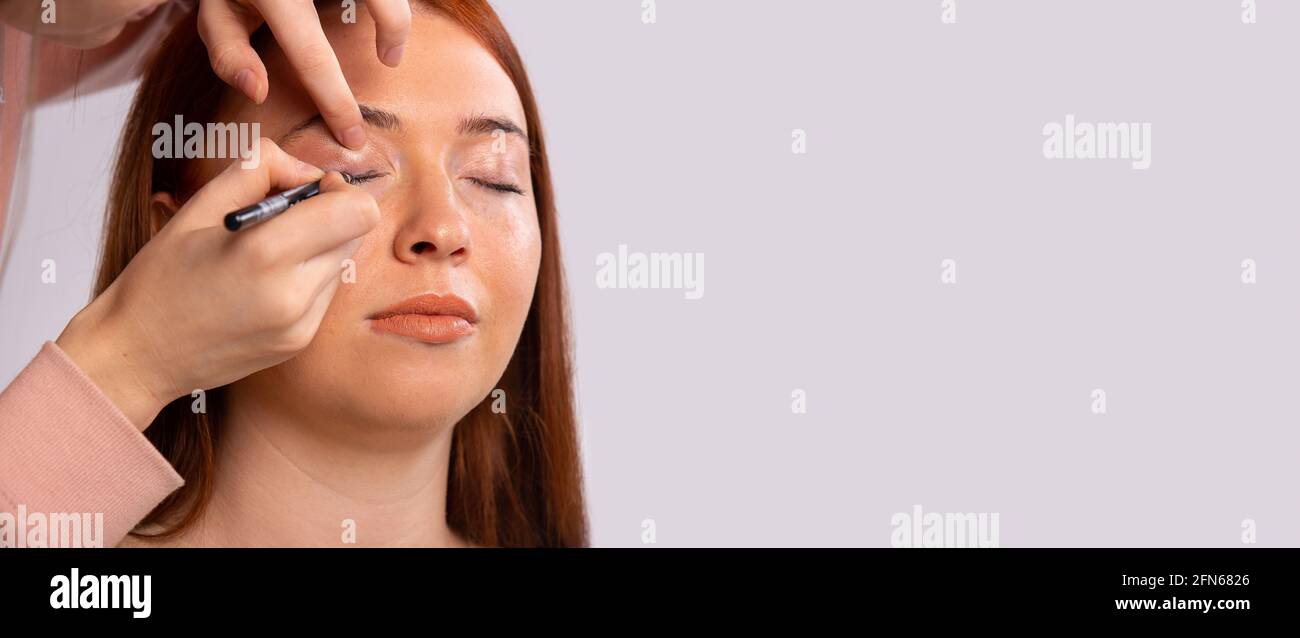 Banner, formato lungo su grigio con ampio spazio per la copia. Concetto per salone di bellezza, etichetta cosmetica, visage e trucco. Eyeliner, occhio femminile e trucco Foto Stock