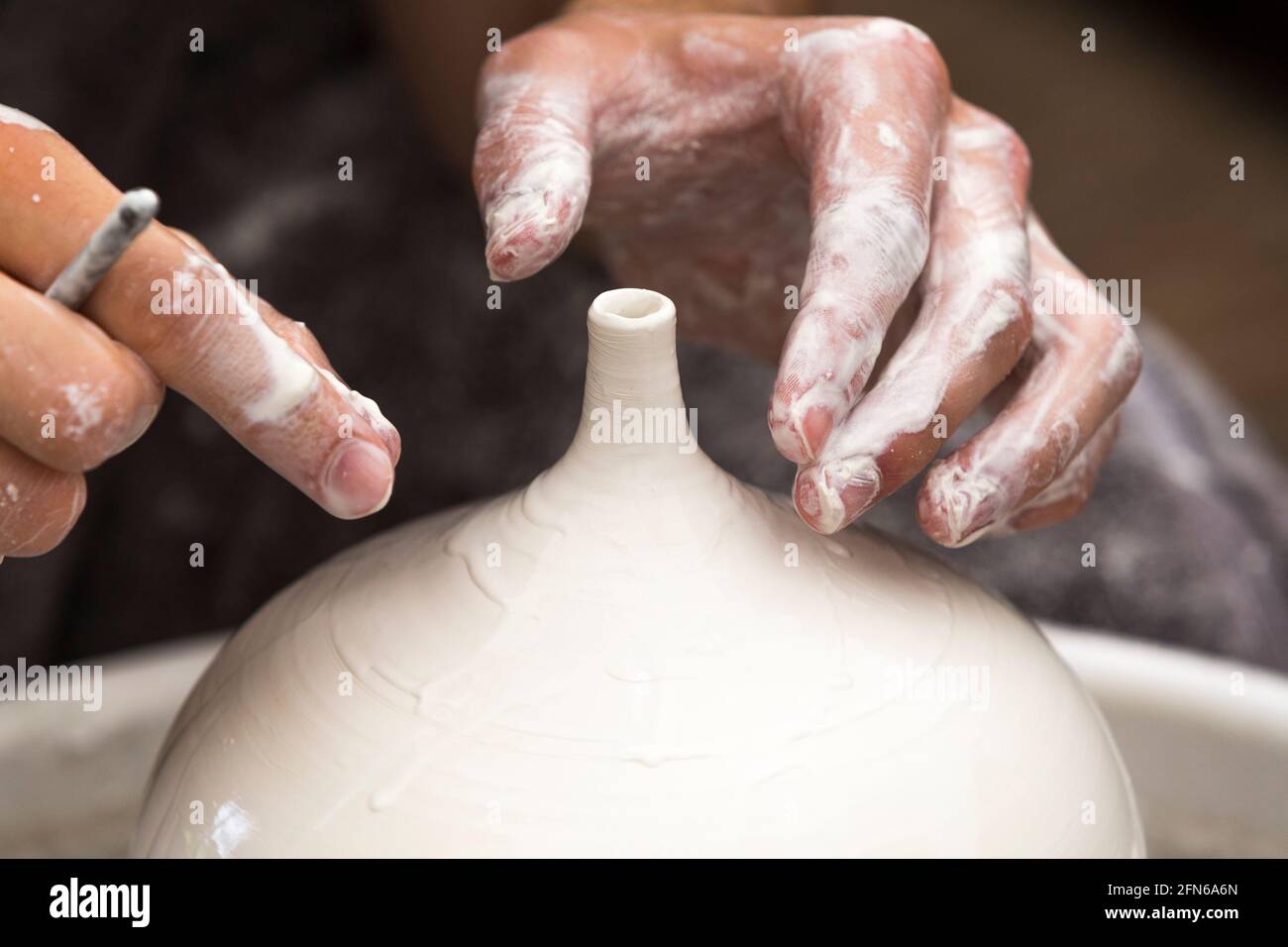 Potter / vasai mani abilmente mano gettando una ceramica gettato vaso di argilla su una ruota di rotazione. Inghilterra. UK (123) Foto Stock