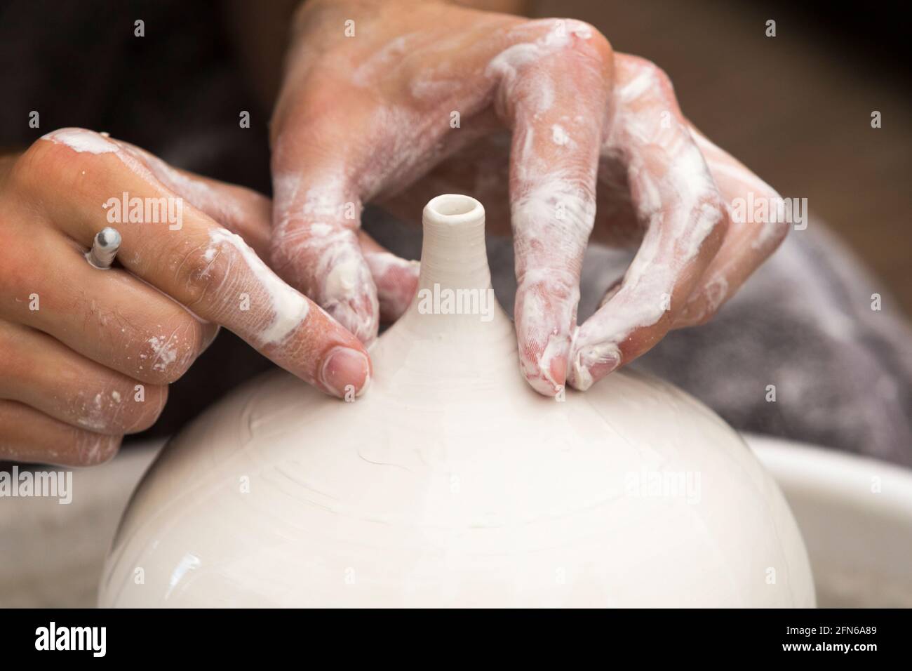 Potter / vasai mani abilmente mano gettando una ceramica gettato vaso di argilla su una ruota di rotazione. Inghilterra. UK (123) Foto Stock