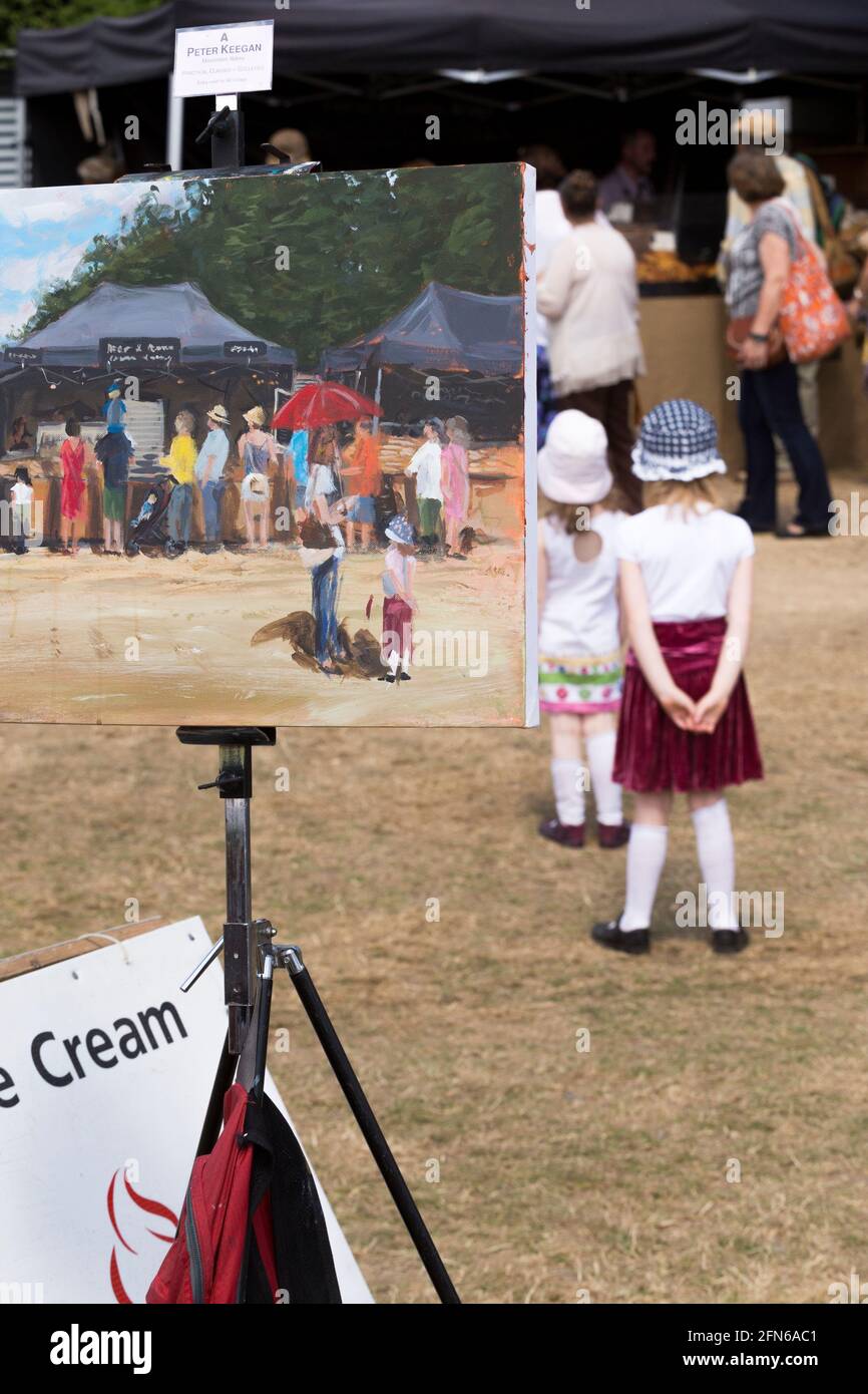 Artista che dipinge una scena in vernice, tra cui una ragazza in gonna rossa, in posa per il pittore. Il campo arabile di una fattoria che si è diversificata è stato riproposto temporaneamente per ospitare il festival. Giornate estive soleggiate con sole e cielo blu. UK (123) Foto Stock