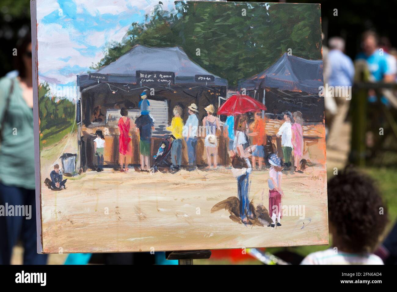 Artista che dipinge una scena in vernice, tra cui una ragazza in gonna rossa, in posa per il pittore. Il campo arabile di una fattoria che si è diversificata è stato riproposto temporaneamente per ospitare il festival. Giornate estive soleggiate con sole e cielo blu. UK (123) Foto Stock