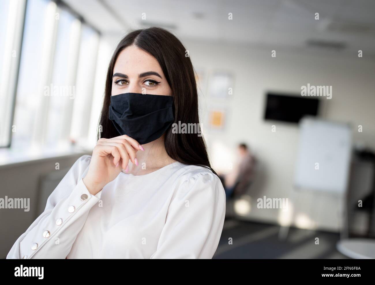 Giovane uomo d'affari che indossa la maschera in ufficio, protezione personale durante COVID-19 Foto Stock