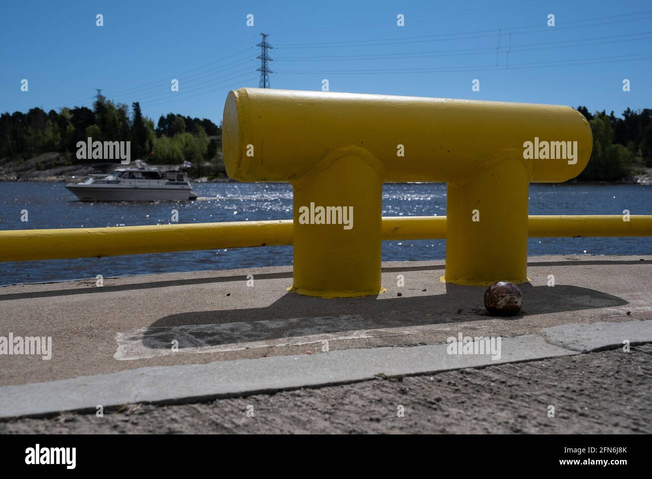 Helsinki / Finlandia - 14 MAGGIO 2021: Closeup di un bollard metallico sul porto con uno yacht che naviga attraverso l'orizzonte sullo sfondo. Foto Stock