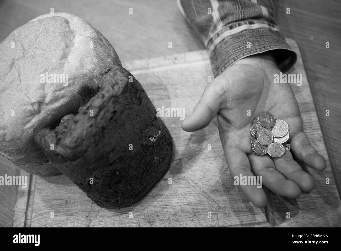 Ultimo denaro per acquistare il pane. Un pane e la mano di un vecchio. Ci sono alcune monete nella palma. Foto Stock