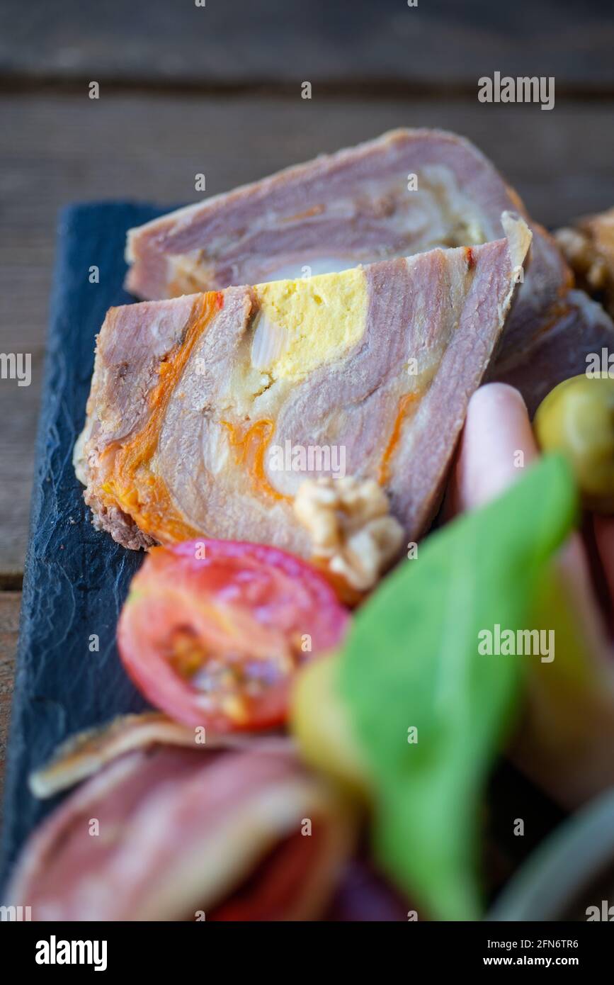 carne di maiale a spirale servita in una tavola con verdure e altri prodotti mediterranei. Foto Stock