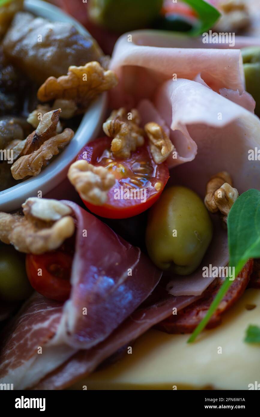 tabella piena di prodotti mediterranei quali frutta a guscio, prosciutto, chee, olive, pomodoro, melanzane. Foto Stock