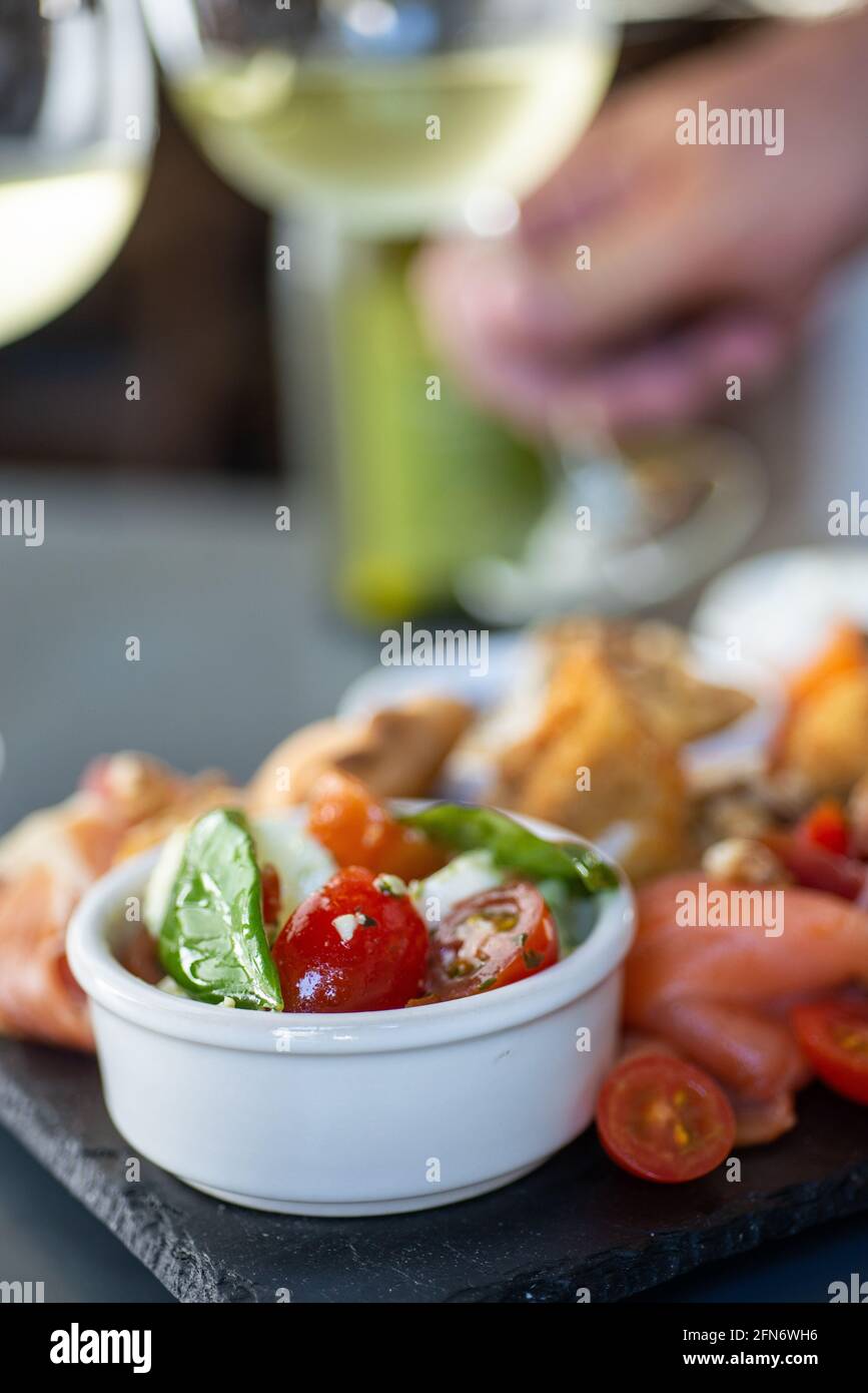 ciotola di pomodoro fresco e antipasti cifferenti con un bianco tazze di vino sullo sfondo Foto Stock