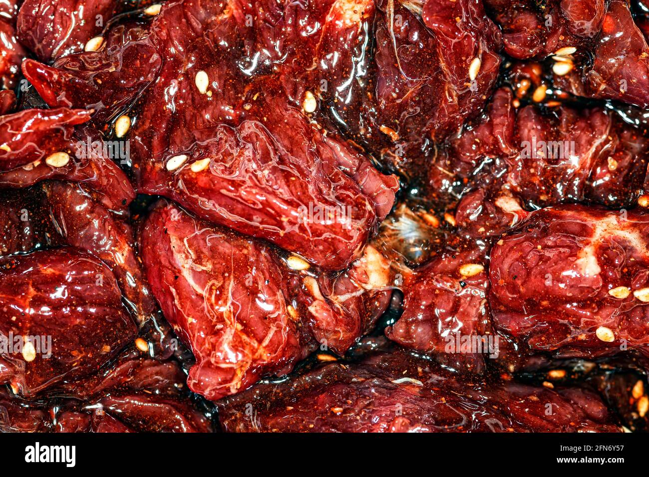 Fette di manzo marinate, luminose e succose, con spezie, olio e semi di sesamo Foto Stock