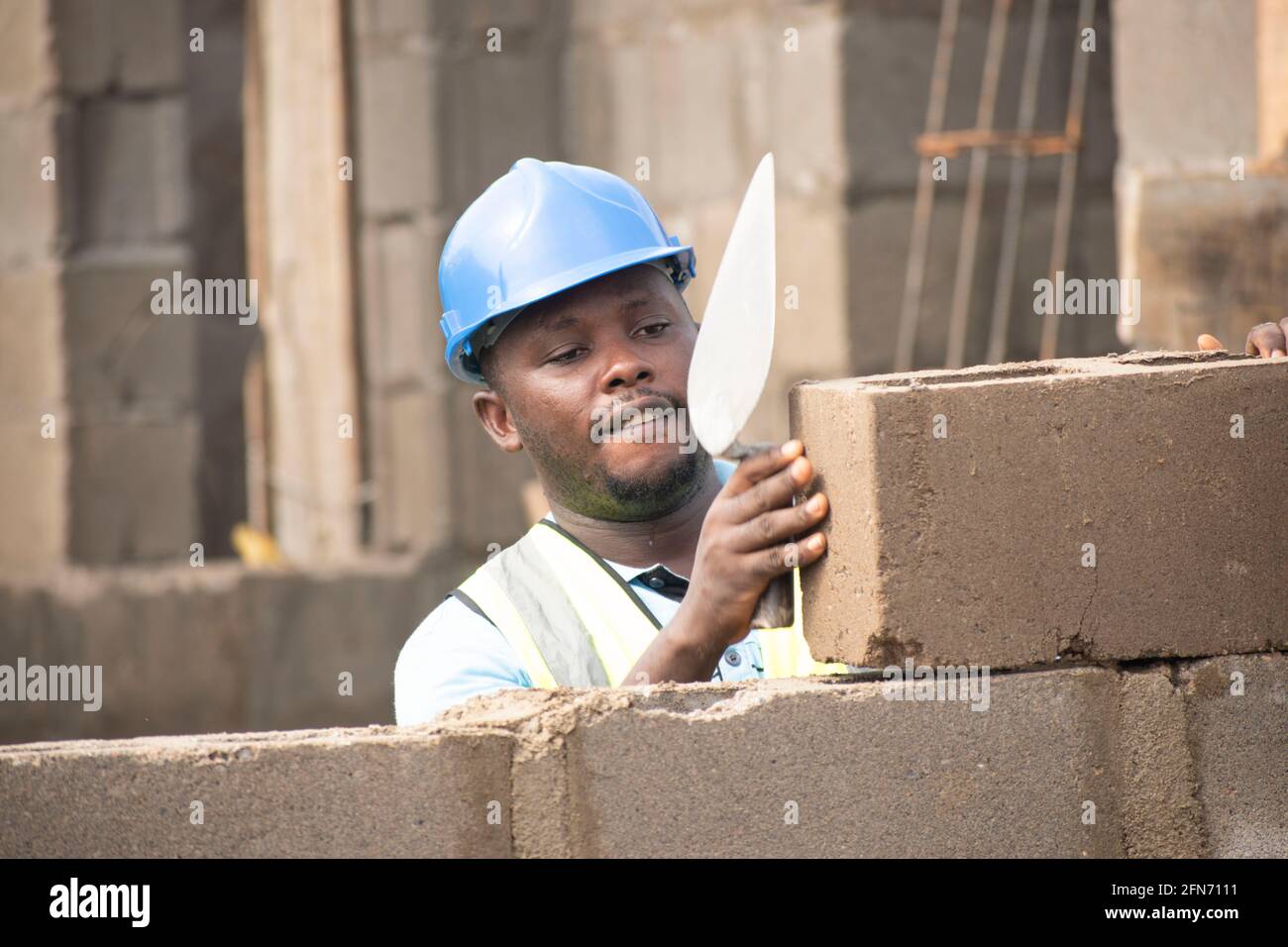un muratore africano che posa mattoni e tiene una cazzuola Foto Stock