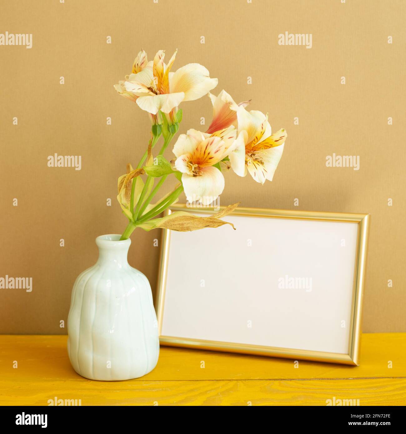 Cornice fotografica vuota con fiori su tavolo di legno. Sfondo marrone Foto Stock