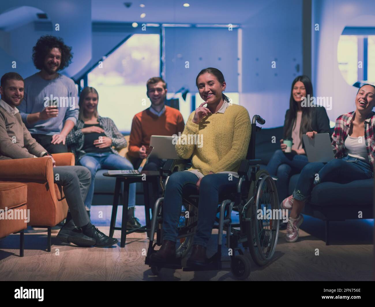 Ritratto di una donna d'affari disabile su una sedia a rotelle di fronte il suo team aziendale in ufficio Foto Stock