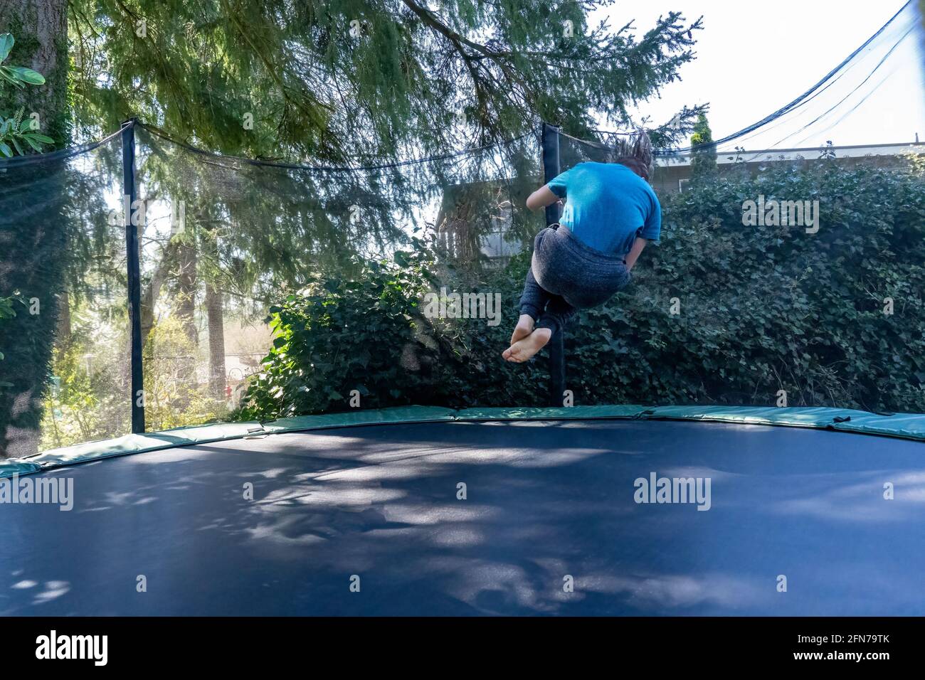 Lynwood, Washington, Stati Uniti. Ragazzo di diciassette anni che rimbalza a mezz'aria su un trampolino nel suo cortile. (SIG.) Foto Stock