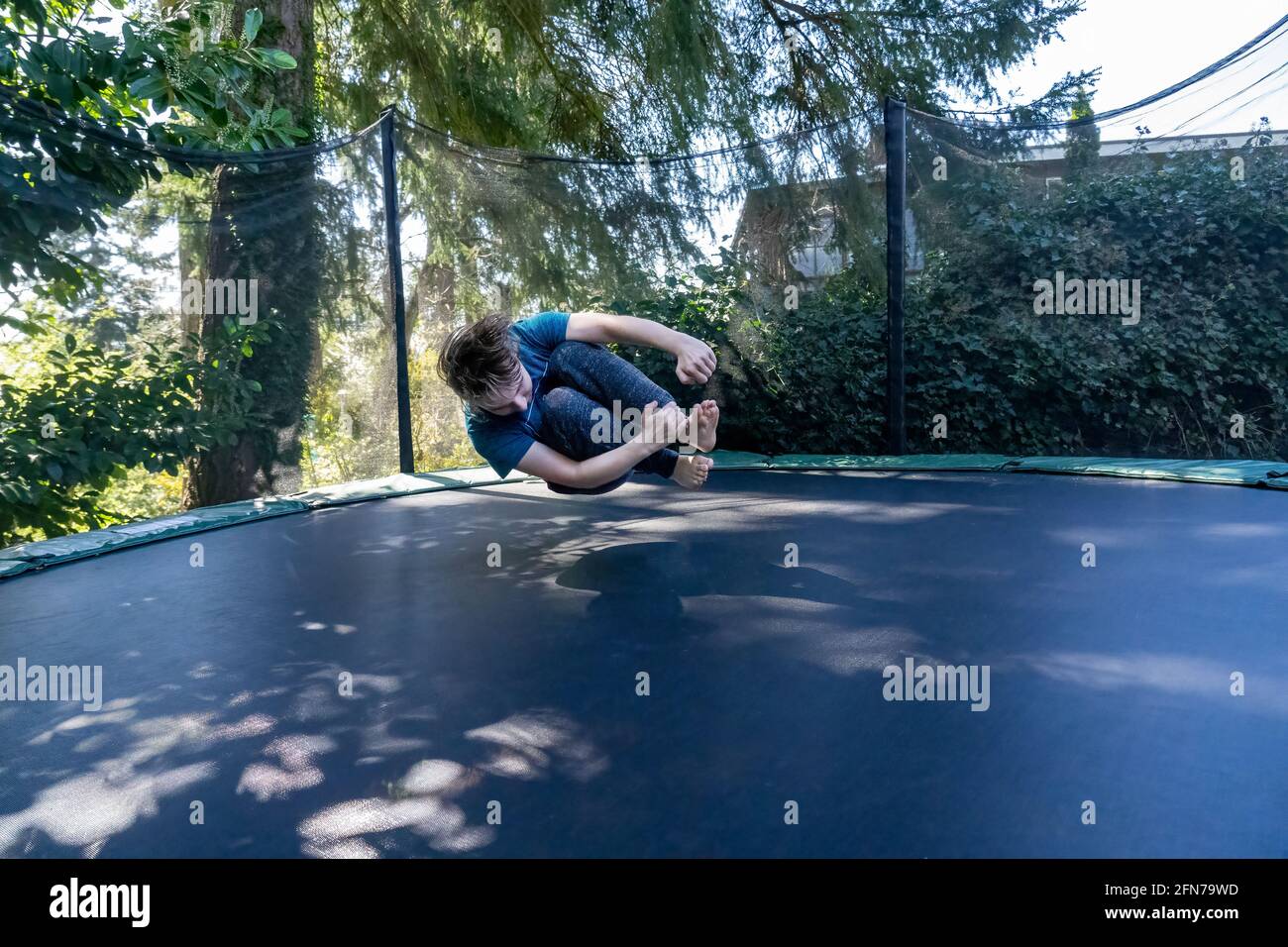 Lynwood, Washington, Stati Uniti. Ragazzo di diciassette anni che rimbalza a mezz'aria su un trampolino nel suo cortile. (SIG.) Foto Stock