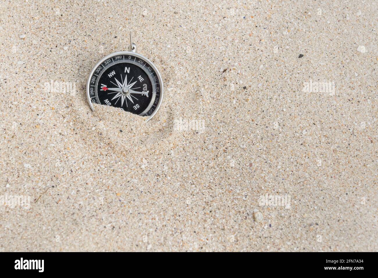 vista frontale dall'alto di una bussola sulla sabbia di una spiaggia di luce naturale Foto Stock