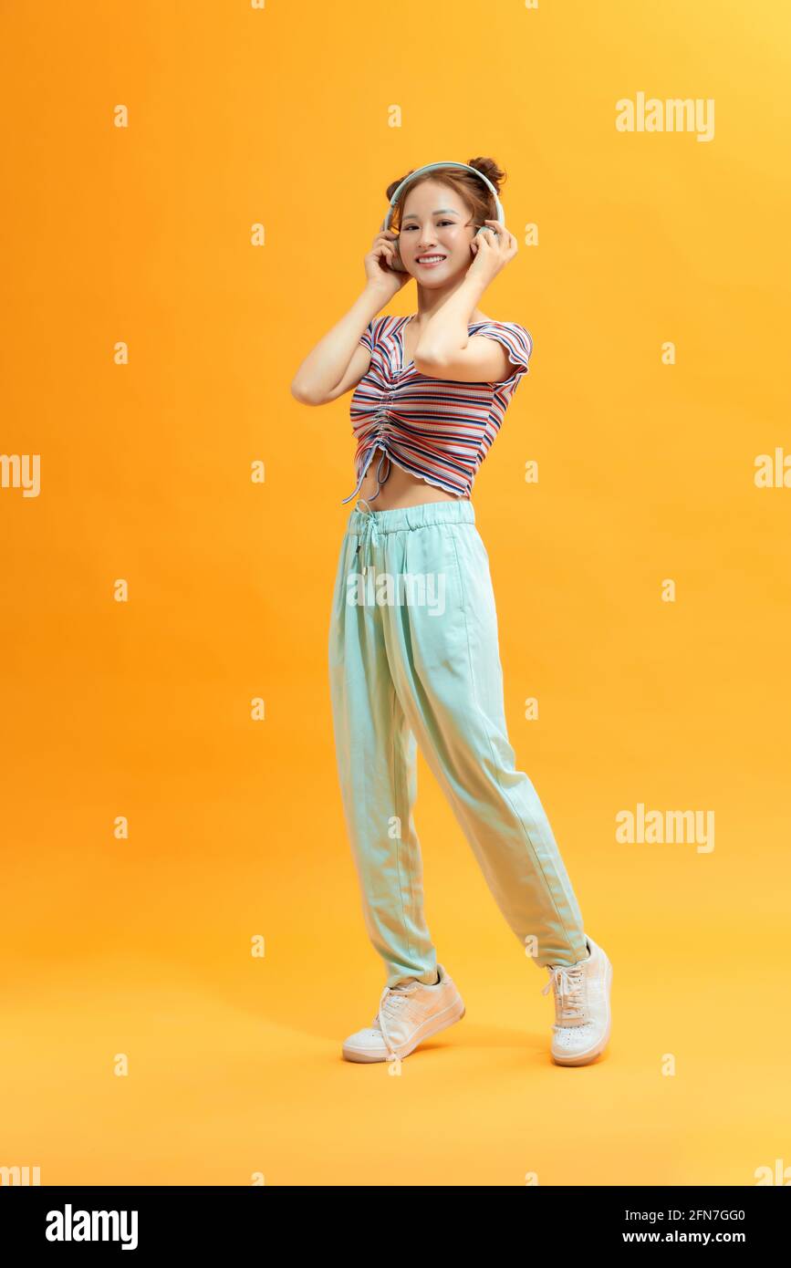 Immagine della giovane giocosa donna che posa su sfondo giallo. Guarda la fotocamera. Foto Stock
