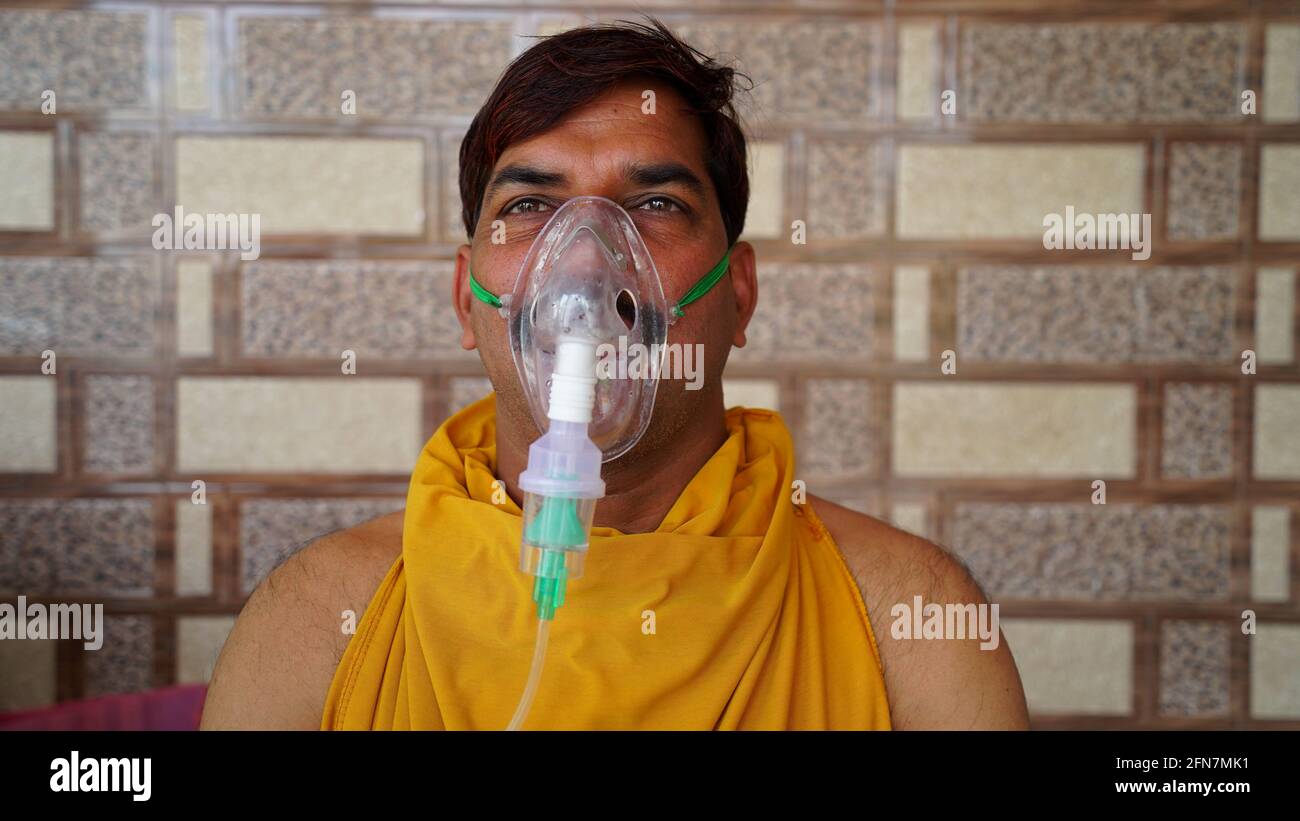 L'uomo indiano infettato con la malattia di Covid 19. Maschera per l'inalazione di ossigeno con flusso di ossigeno liquido. Foto Stock