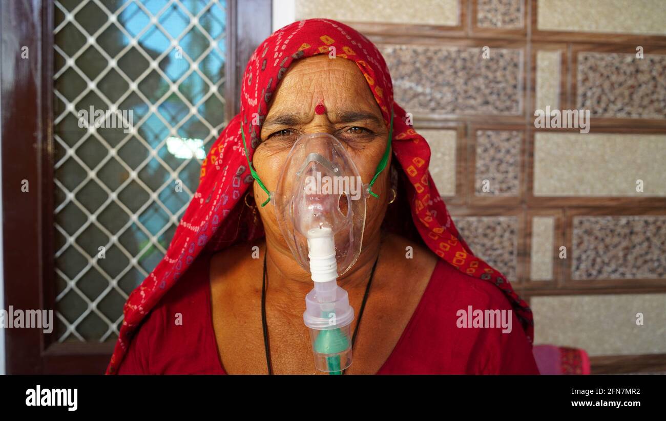 03 maggio 2021 - Reengus, Sikar, India. Vecchia donna indiana infettata con la malattia di Covid 19. Maschera per l'inalazione di ossigeno con flusso di ossigeno liquido. Foto Stock