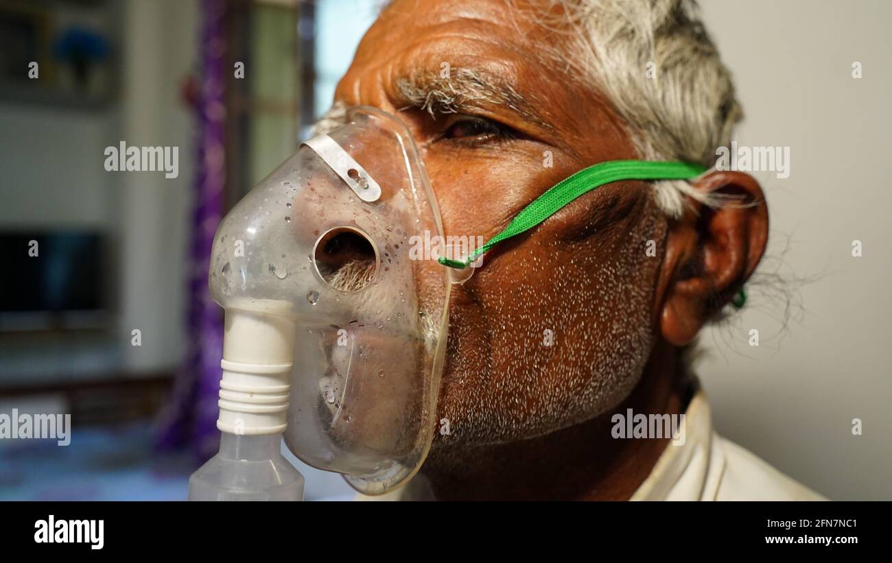 03 maggio 2021 - Reengus, Sikar, India. Vecchio uomo indiano infettato con la malattia di Covid 19. Maschera per l'inalazione di ossigeno con flusso di ossigeno liquido. Foto Stock
