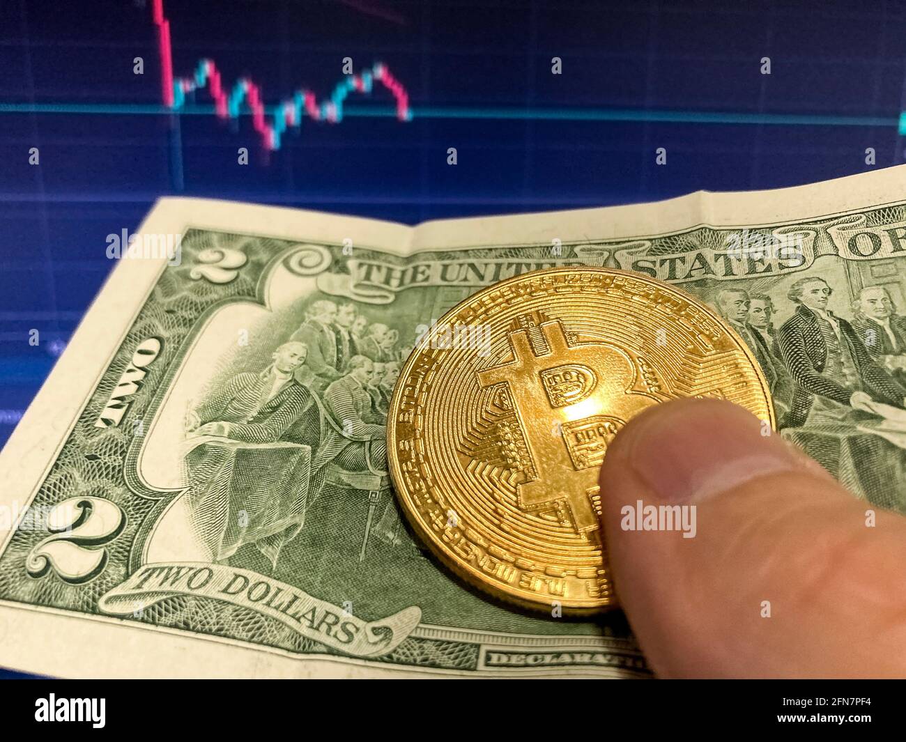 Moneta di Bitcoin su fattura di carta due dollari, USD - sfondo sfocato. Il programma elettronico di bitcoin, volumi commerciali Foto Stock