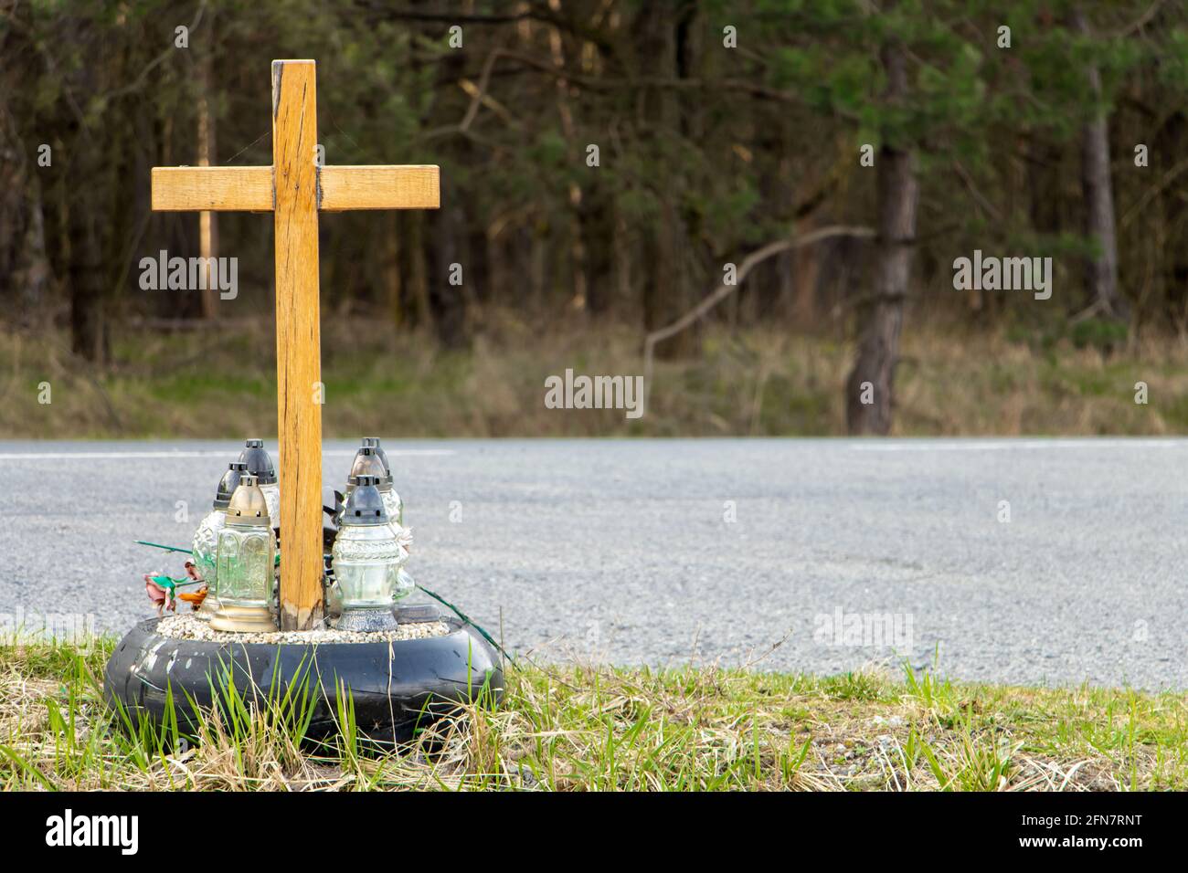 Una croce commemorativa a lato della strada con candele che commemorano la tragica morte accanto a una strada. Foto Stock