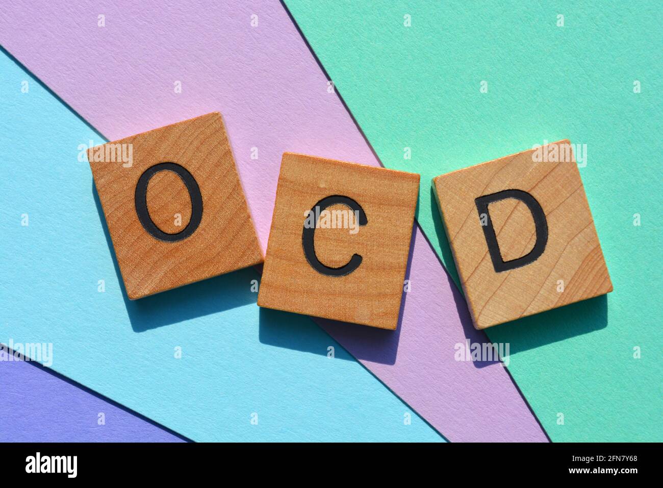 OCD acronimo di disturbo compulsivo ossessivo in lettere alfabetiche in legno su sfondo colorato Foto Stock