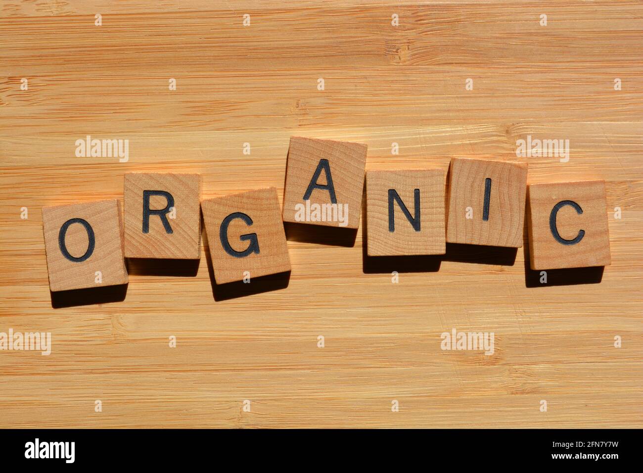 Organico, parola in lettere alfabetiche di legno isolato su sfondo di legno di bambù Foto Stock