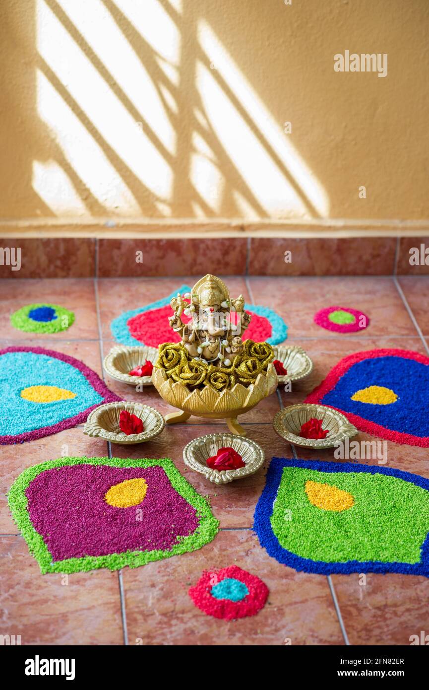 Scultura dorata del dio Ganesha circondata da petali rangoli Foto Stock