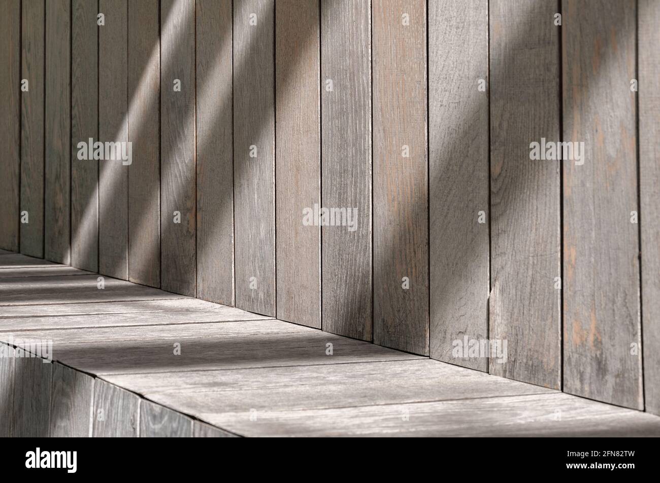 Parcheggia la panchina in primo piano, un luogo dove sedersi. Tavole leggere in legno, graffiate, invecchiate e sbiadite, con la luce solare che cade su di loro Foto Stock