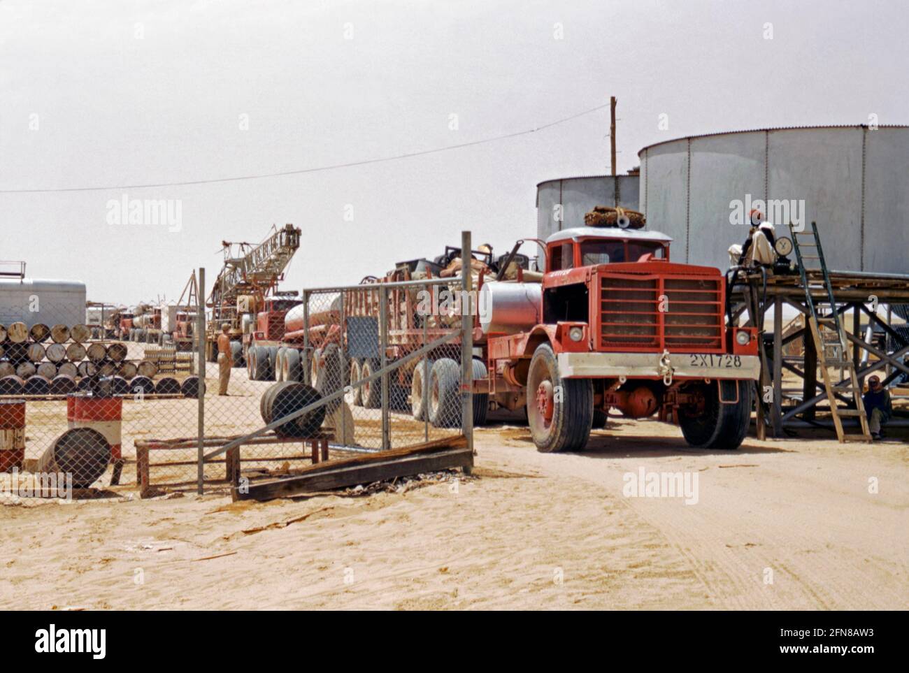 Esplorazione petrolifera della compagnia petrolifera Aramco in Arabia Saudita c. 1955. Qui un convoglio di camion lascia un deposito per dirigersi verso i siti di esplorazione. I veicoli trasportano attrezzature da campeggio, case mobili/uffici e carri di prova-perforazione. Le petroliere fanno parte del convoglio. Saudi Aramco (ora Saudi Arabian Oil Company e ex Arabian-American Oil Company) è una società Saudita di petrolio e gas naturale con sede a Dhahran. . Nel 1944 il nome della società è stato cambiato da California-Arabian Standard Oil Company a Arabian-American Oil Company (o Aramco), una fotografia degli anni '50. Foto Stock