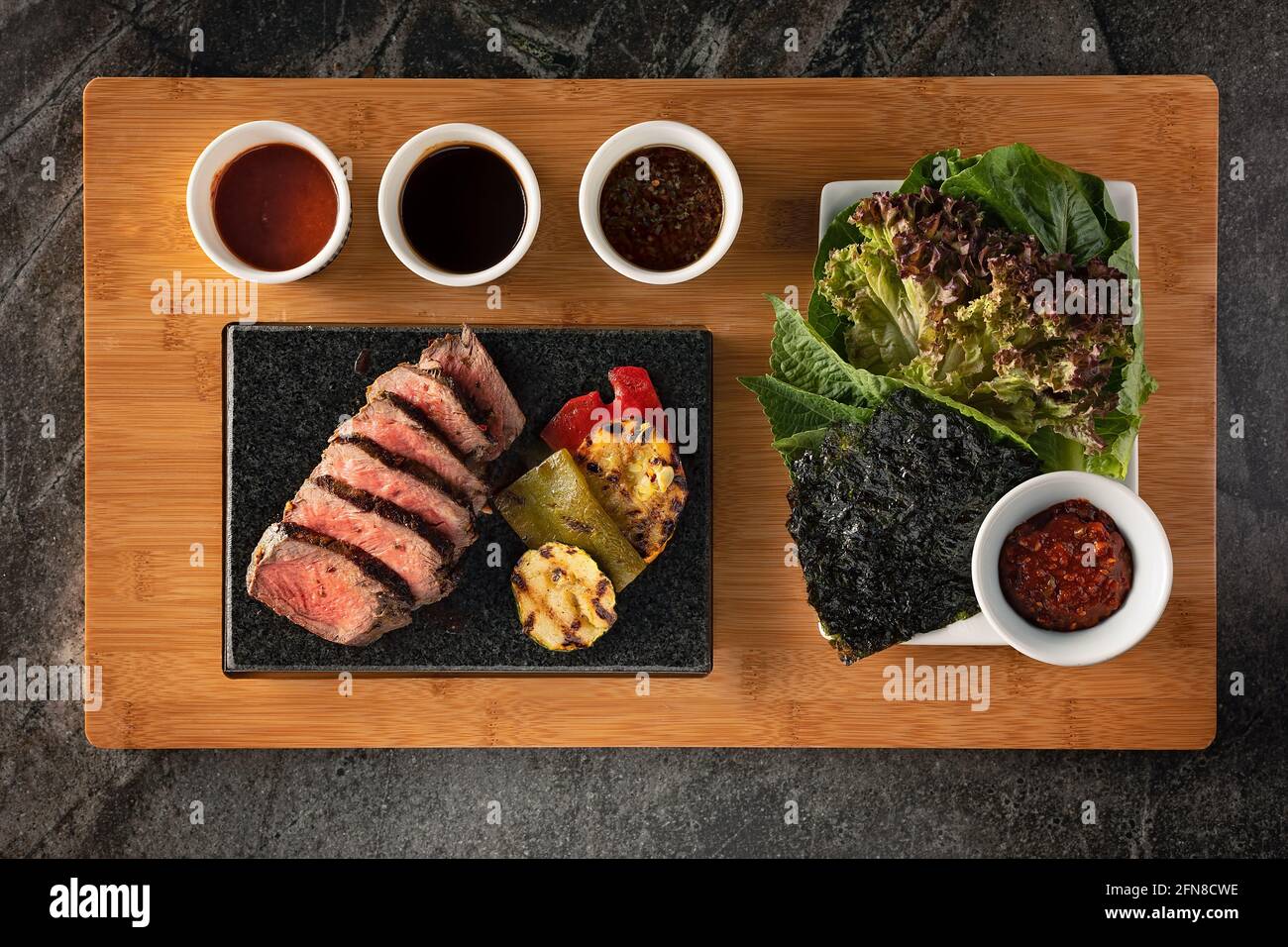 Completa un piatto di manzo con verdure, salse e insalate durante una cena barbecue coreana Foto Stock