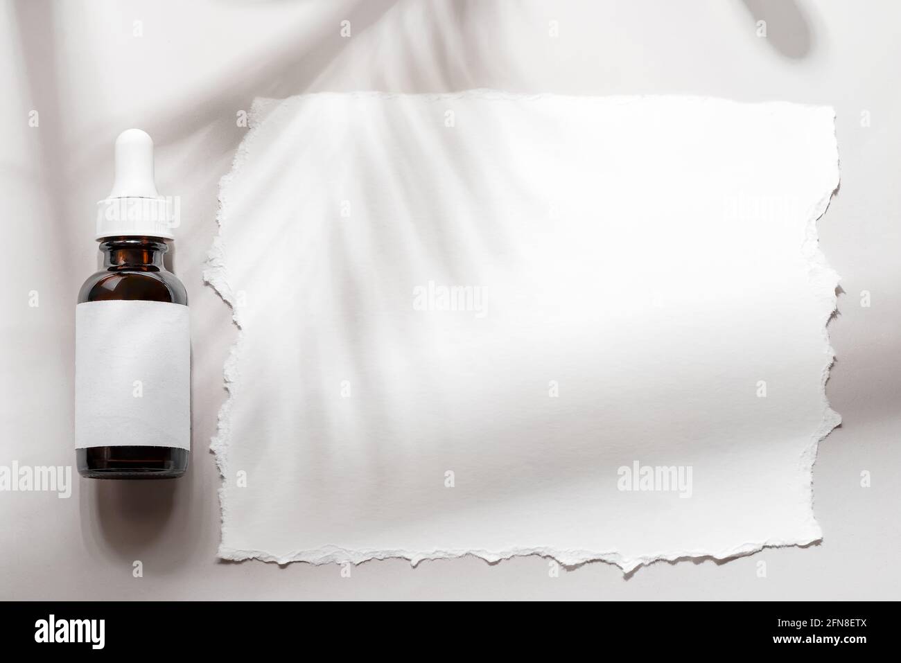 Pipettare il flacone marrone cosmetico mockup con carta sulle ombre grigie sfondo Foto Stock