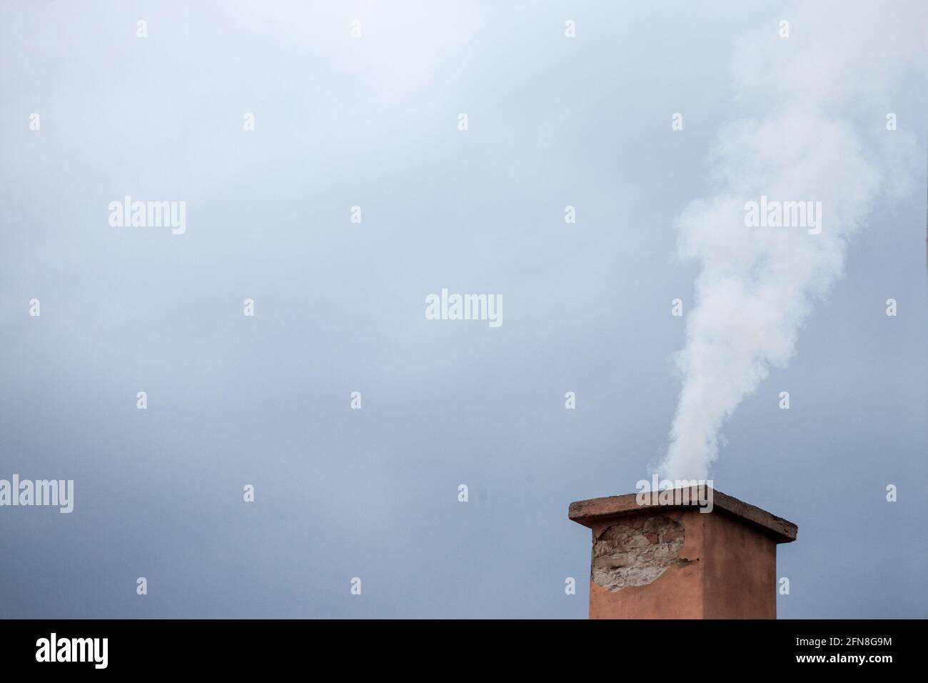 Immagine del tetto di una casa residenziale con un fuoco sul suo camino, utilizzato per il riscaldamento, rejeting un po 'di fumi bianchi Foto Stock